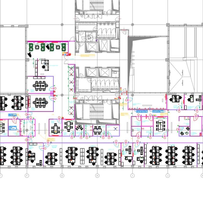 Techniczny rzut płaski kondygnacji biurowej w formie rysunku CAD. Plan pokazuje układ licznych stanowisk pracy typu open space, sal konferencyjnych oraz ciągów komunikacyjnych zaznaczonych kolorowymi liniami.